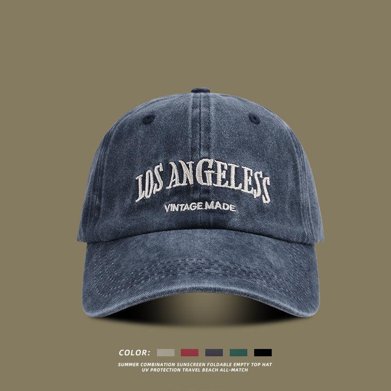 Navy blue washed cotton baseball cap with white embroidered Los Angeles text and color selection options below