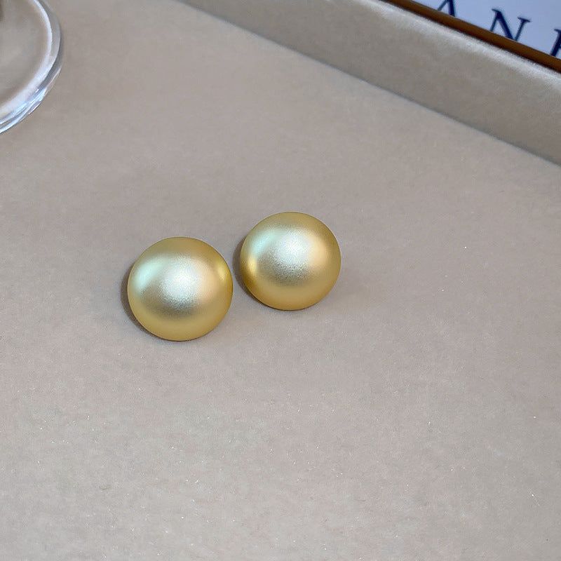 Matte gold dome stud earrings on grey background, minimalist design