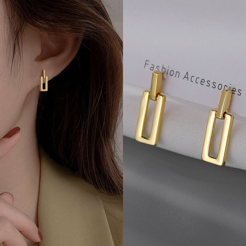 Gold geometric square drop earrings on fashion accessory display