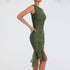 A model is wearing a fitted olive green ruched dress with asymmetrical ruffle hem, standing against a white background