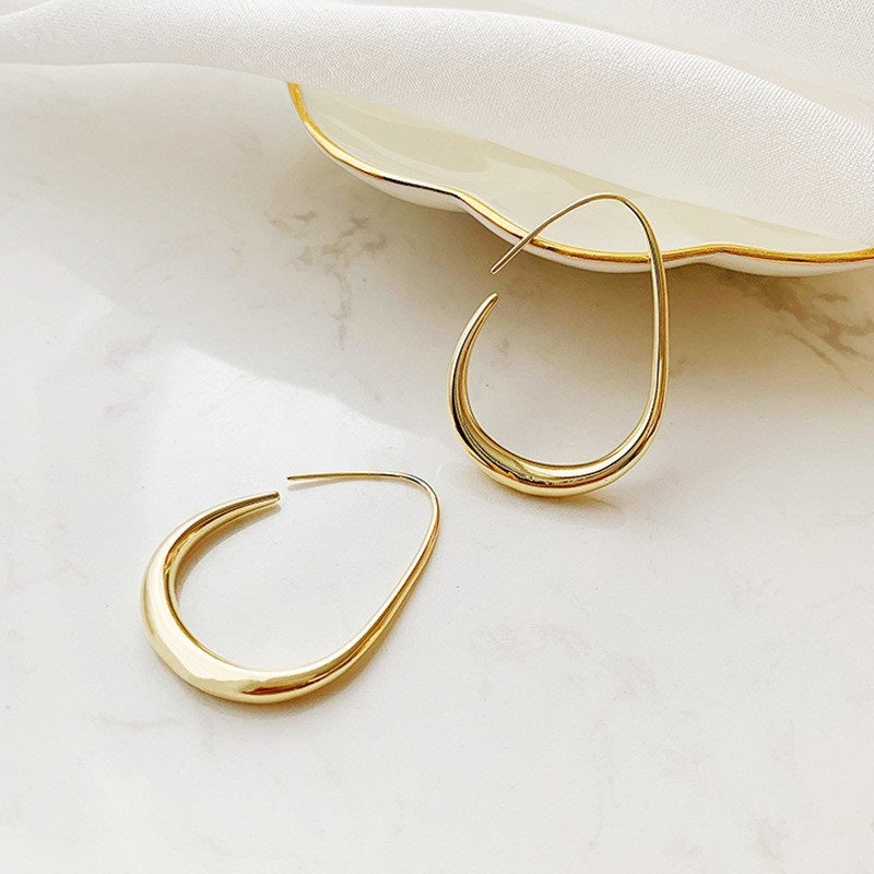 Teardrop-shaped gold hoop earrings with curved design