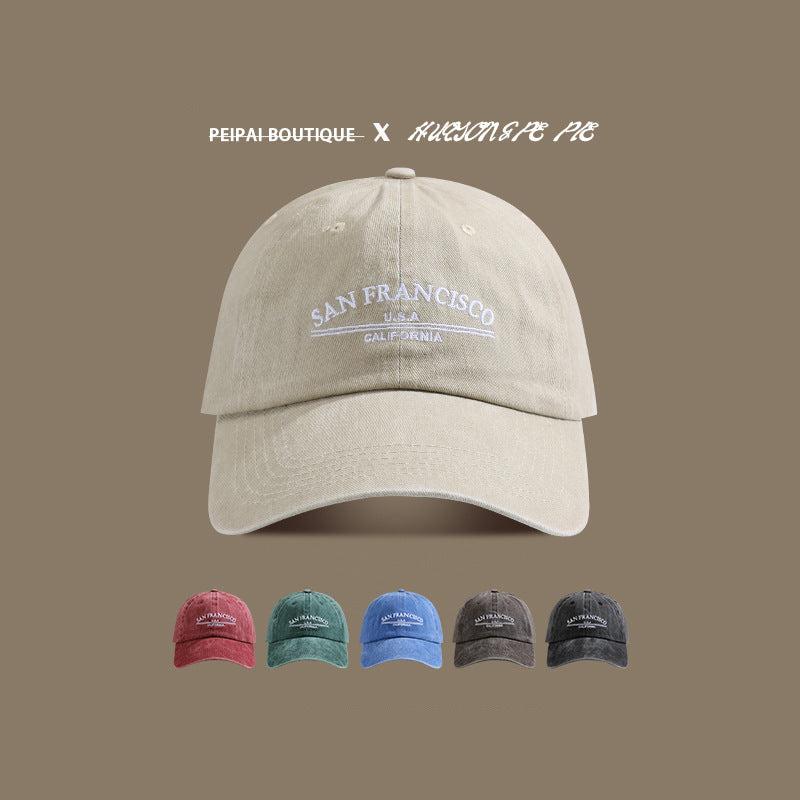 A beige washed cotton baseball cap with white 'San Francisco USA California' embroidery shown against taupe background with color options below