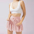 Soft pink tiered tennis skirt with high waistband and drawstring detail, paired with white sports bra