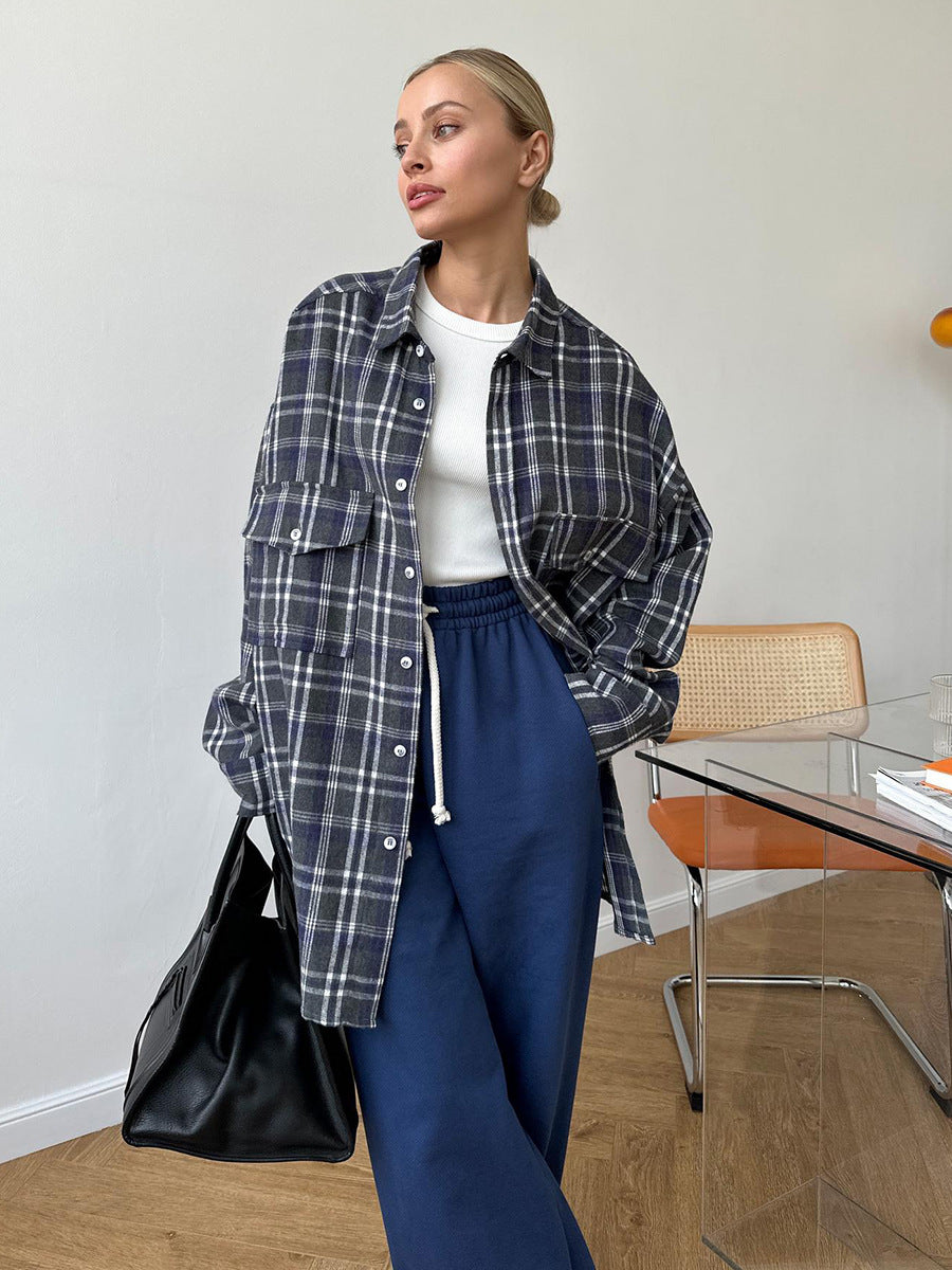 Navy blue plaid oversized shirt jacket paired with white top and navy sweatpants, modern minimalist outfit against white wall