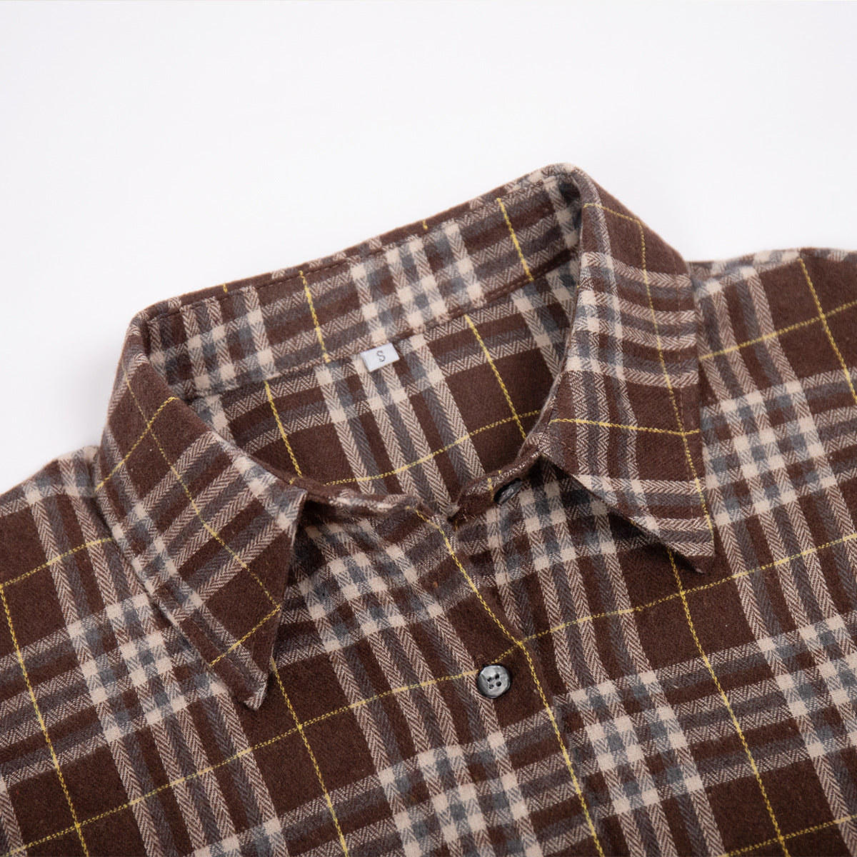 Detail shot of shirt collar and button placket in brown plaid pattern with size label