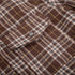 Macro texture shot of brown plaid fabric showing detailed herringbone weave and button closure