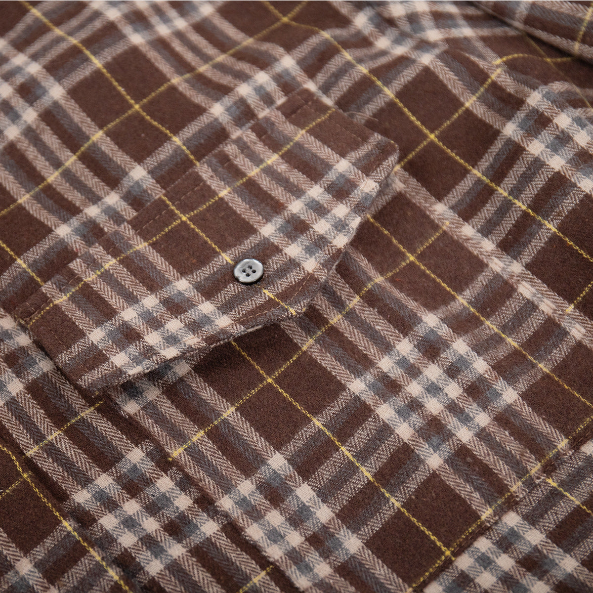 Macro texture shot of brown plaid fabric showing detailed herringbone weave and button closure