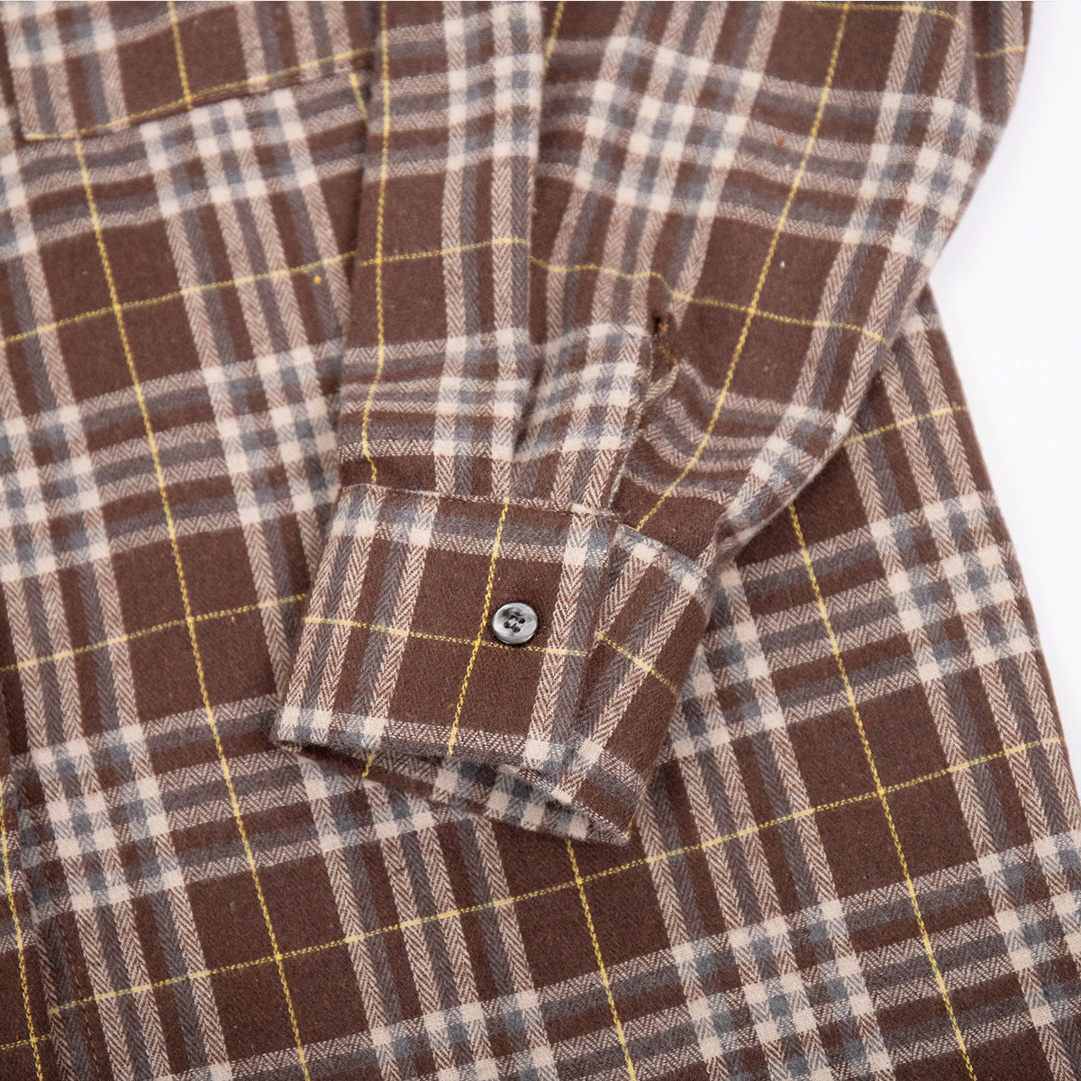 Close-up of shirt cuff detail showing button closure and plaid pattern alignment