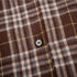 Extreme close-up of four-hole button on brown plaid fabric showing stitching detail