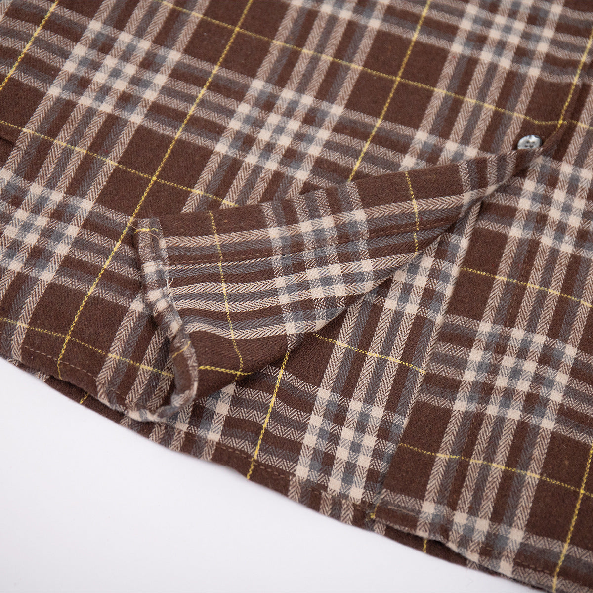 Detail shot of chest pocket construction on brown plaid flannel shirt showing pattern matching