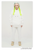 Model with platinum hair and neon green braids wearing an all-white sweatsuit set, featuring hoodie and matching pants with beige footwear against minimal backdrop