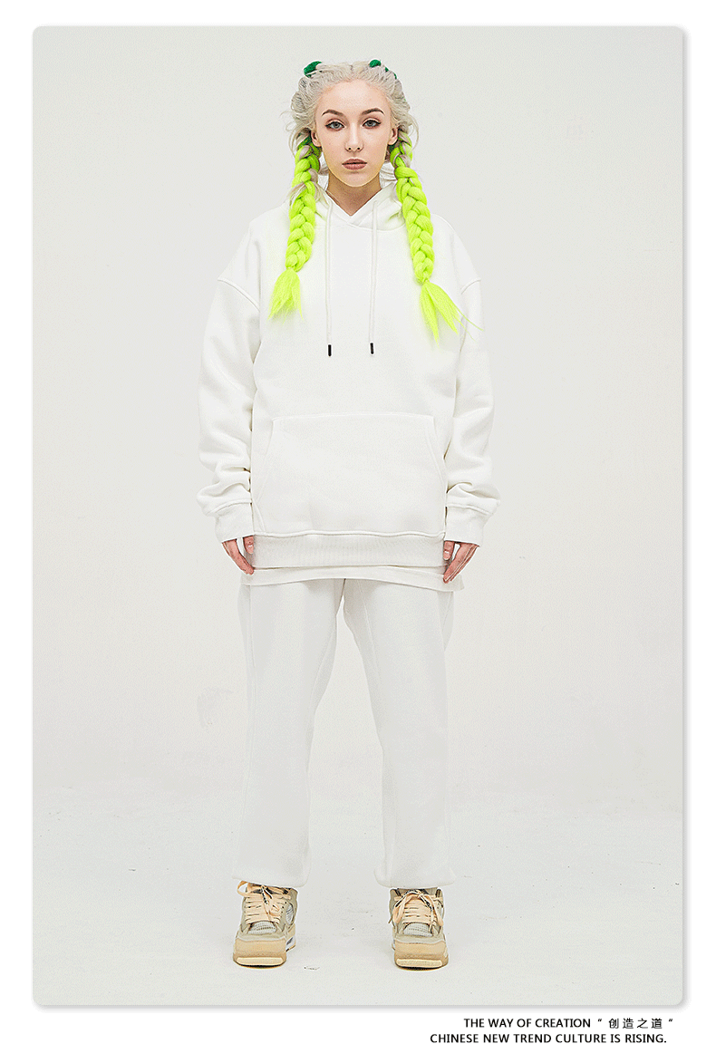 Model with platinum hair and neon yellow braids wearing a white sweatsuit with oversized hoodie and matching joggers
