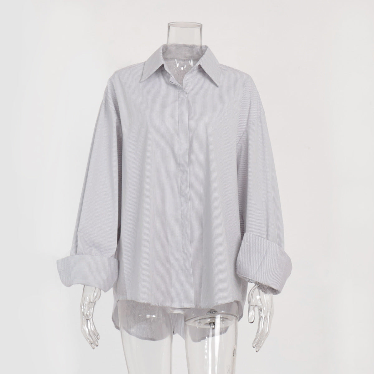 A white mannequin is wearing a gray striped oversized button-up shirt with rolled-up sleeves against a plain background