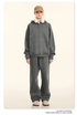 Blonde model wearing charcoal gray oversized zip-up hoodie and sweatpants with tan cap, white headphones and beige shoes against cream background