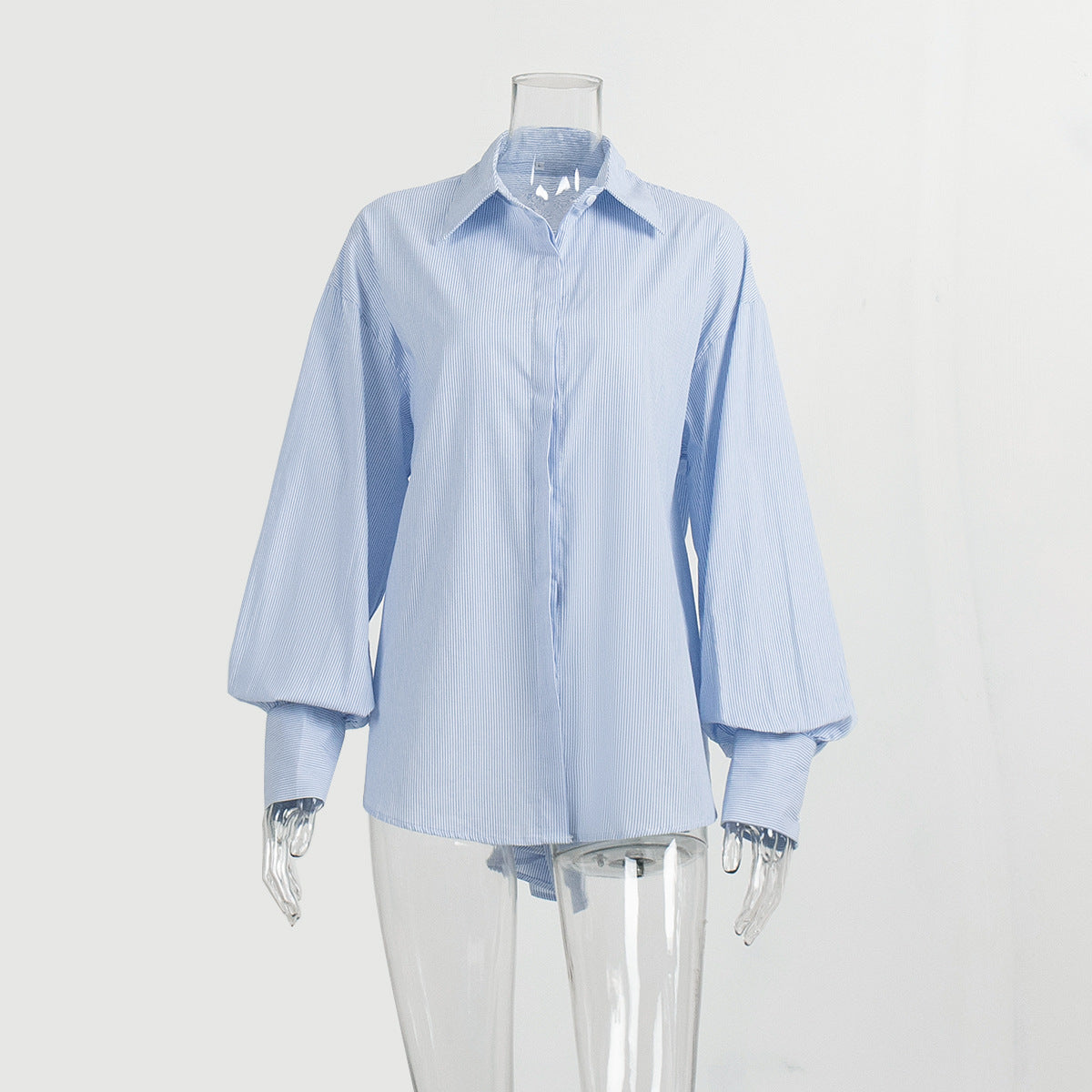 A white mannequin is wearing a blue striped oversized button-up shirt with balloon sleeves, buttoned up, against a plain background