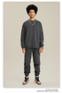 Male model wearing dark gray sweatsuit set with silver chain necklace, red watch and brown/white Jordan sneakers