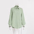A sage green textured cotton button-down shirt with collar and balloon sleeves displayed on transparent mannequin against white background
