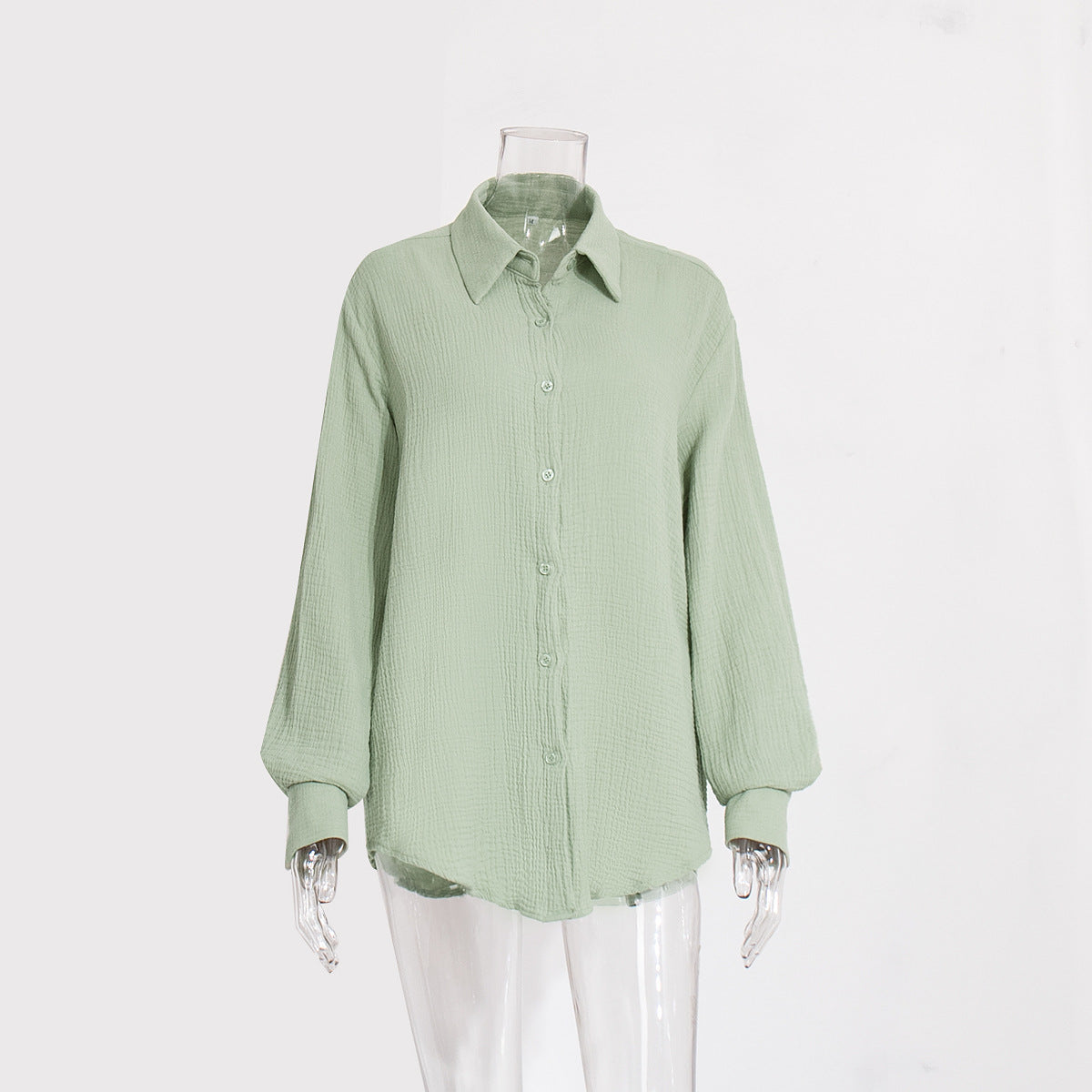 A sage green textured cotton button-down shirt with collar and balloon sleeves displayed on transparent mannequin against white background