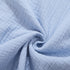 A close-up of light blue textured cotton fabric showing the crinkled gauze material with natural wrinkles against light background