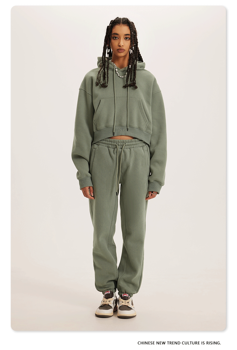 Muted Green Sweatshirt and Joggers Set – Model wears a sage green cropped hoodie and matching sweatpants with sneakers