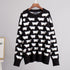 Black knit sweater with contrasting white sheep pattern on wooden hanger