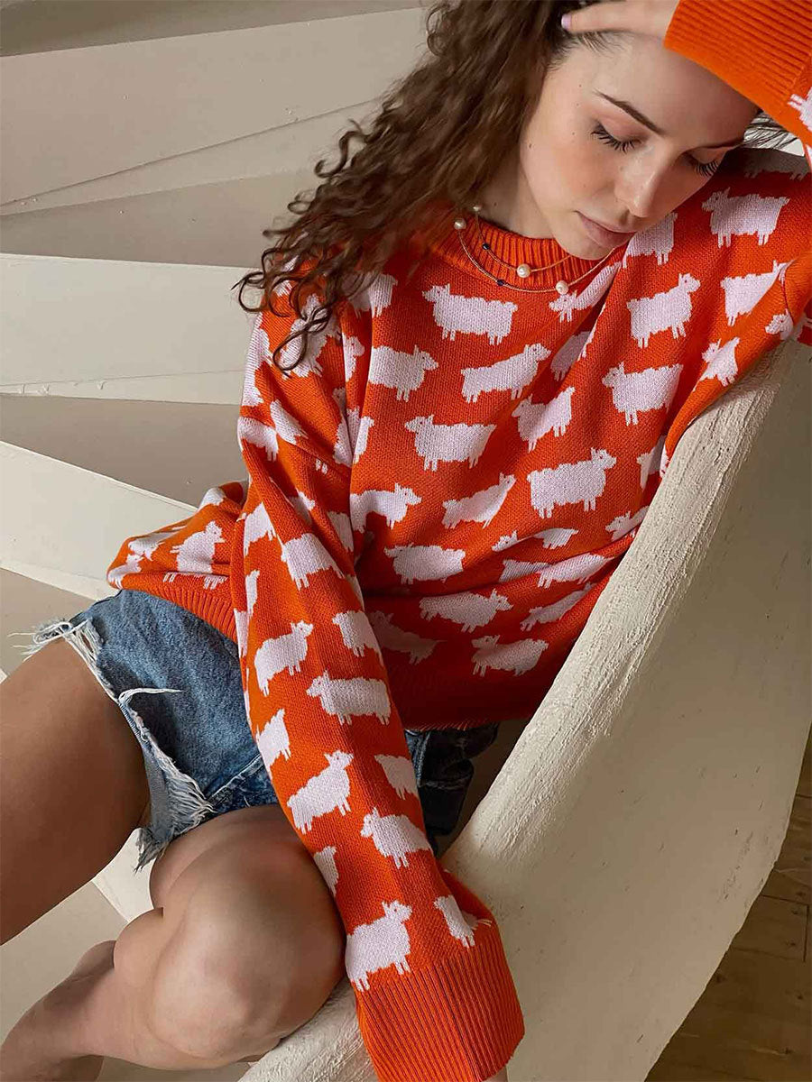 Orange knit sweater with white sheep print pattern styled with denim shorts