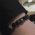 Black stone bracelet worn on wrist with black sleeve, showing gold star charm detail