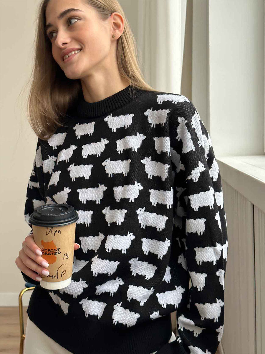 Black knit sweater with white sheep pattern print, styled with coffee cup