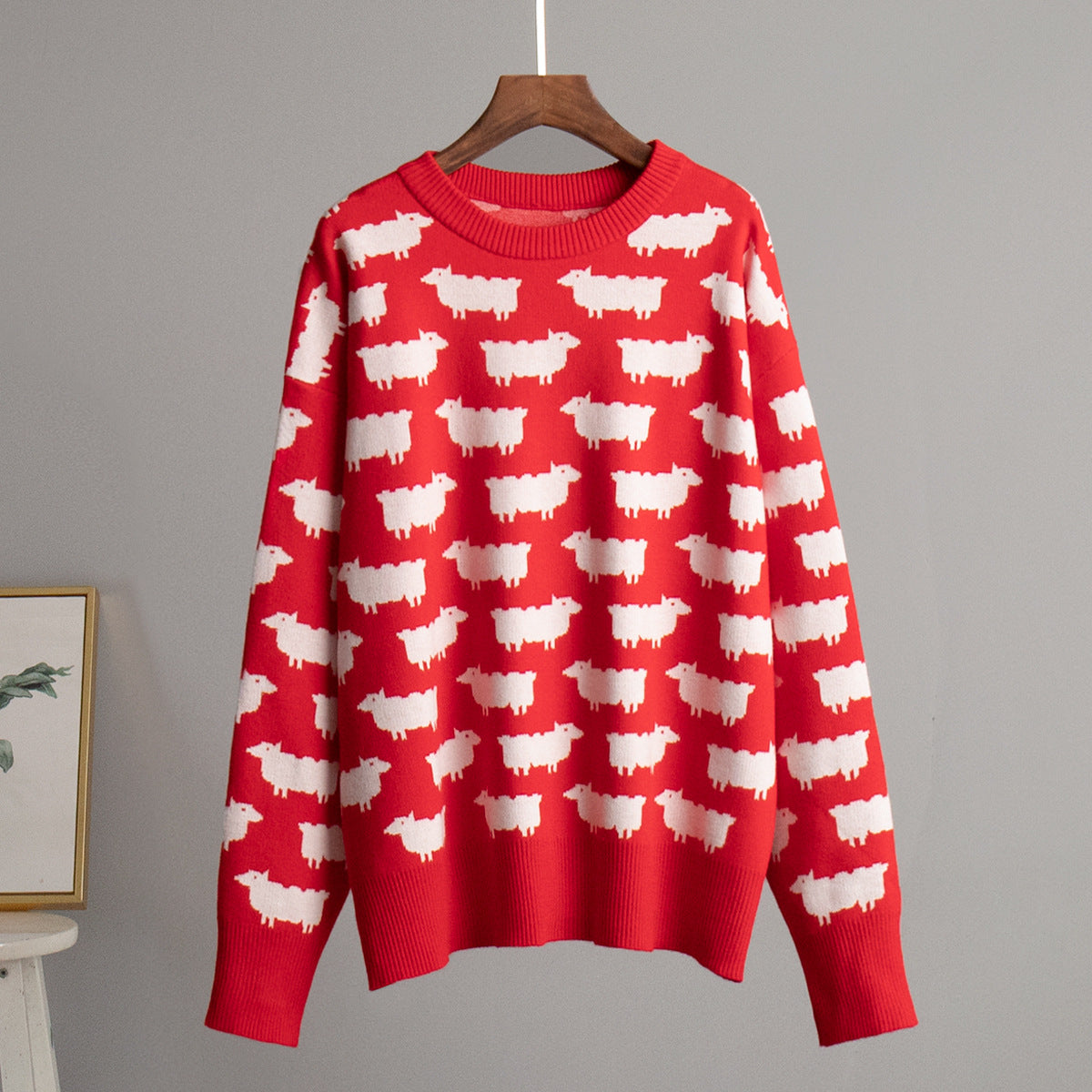 Red crew neck sweater with all-over white sheep pattern on display hanger