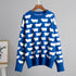 Royal blue sweater with repeating white sheep motif on wooden hanger