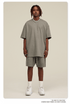 Close-up front view of man in sage green oversized T-shirt and matching shorts with silver chain necklace