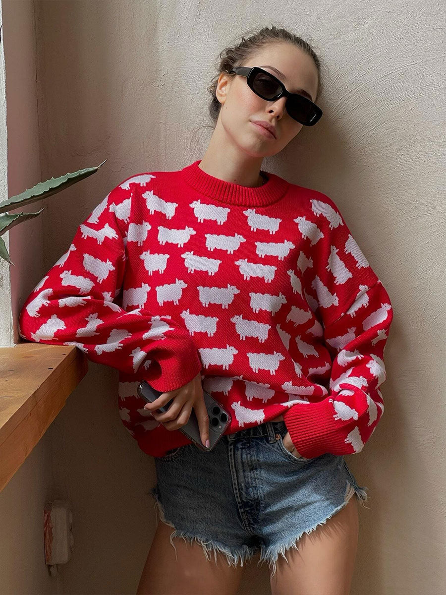 Red knit sweater with white sheep pattern worn with denim shorts and black sunglasses