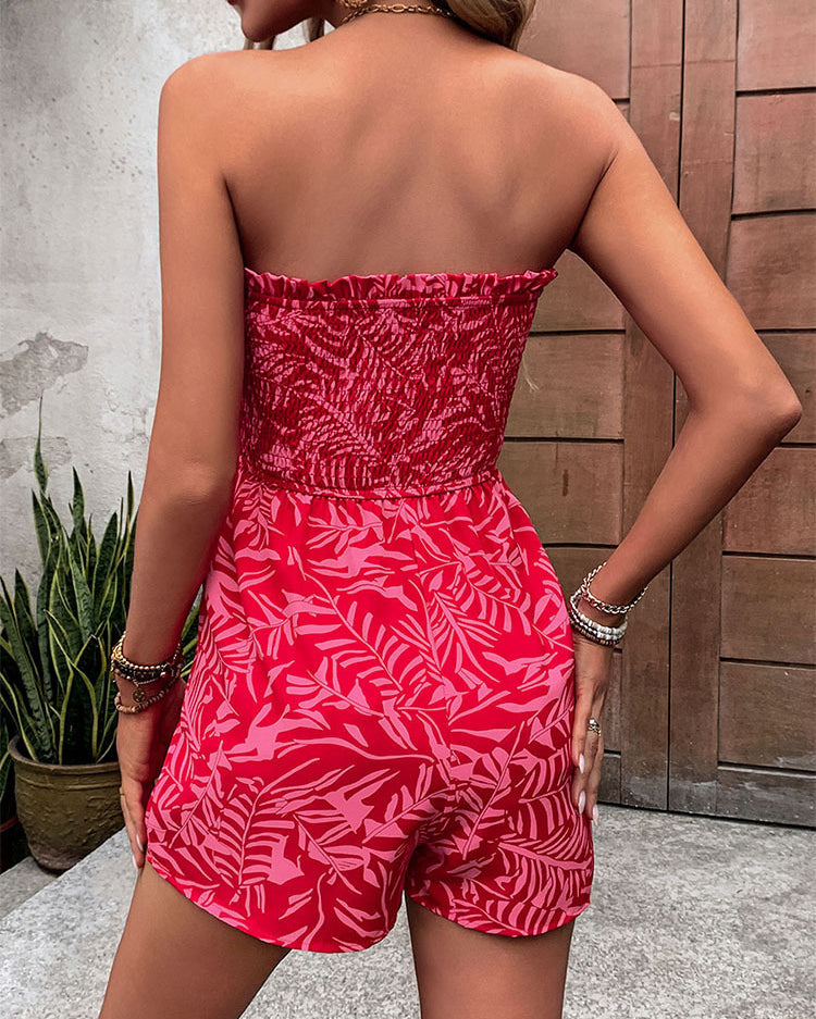 Back view of a woman in a red strapless tropical print romper, showing smocked detail on top.