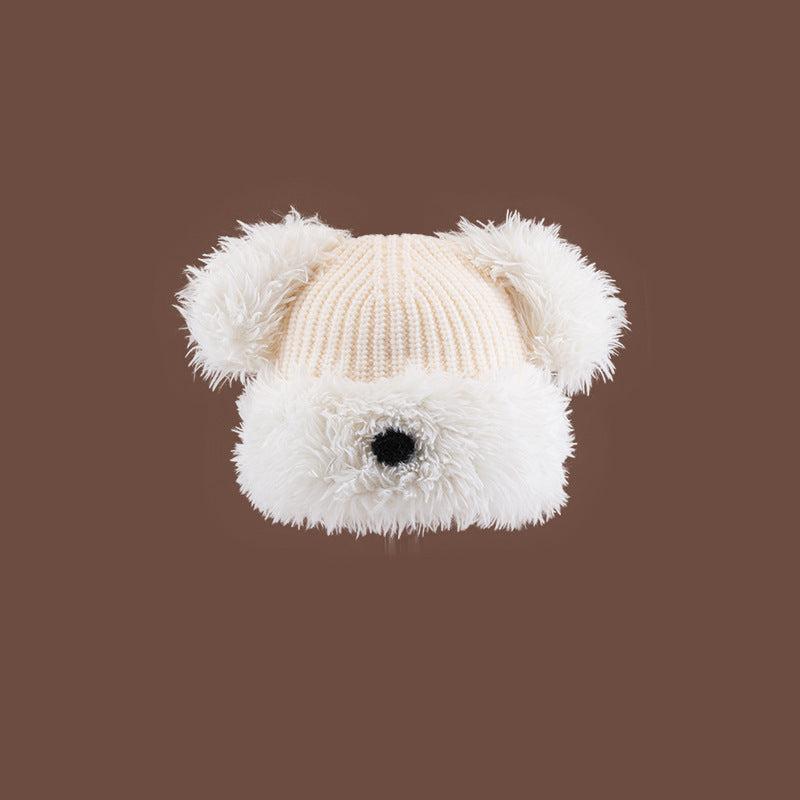White Dog Nose Plush Knit Beanie with plush faux fur trim and pom pom ears against brown backdrop