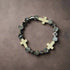A stretch bracelet with a mix of black, gray, and white beads, featuring white cross-shaped beads and silver cross charms.
