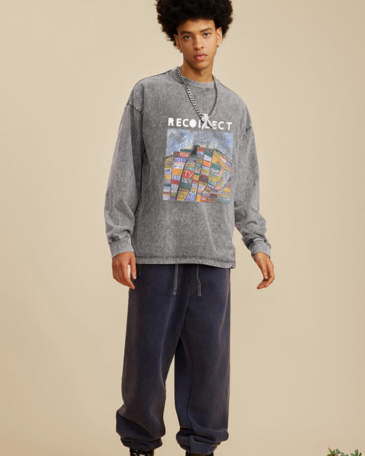 A male model wears a gray oversized "RECOLLECT" sweatshirt with a colorful print, navy sweatpants, and sneakers, posing neutrally