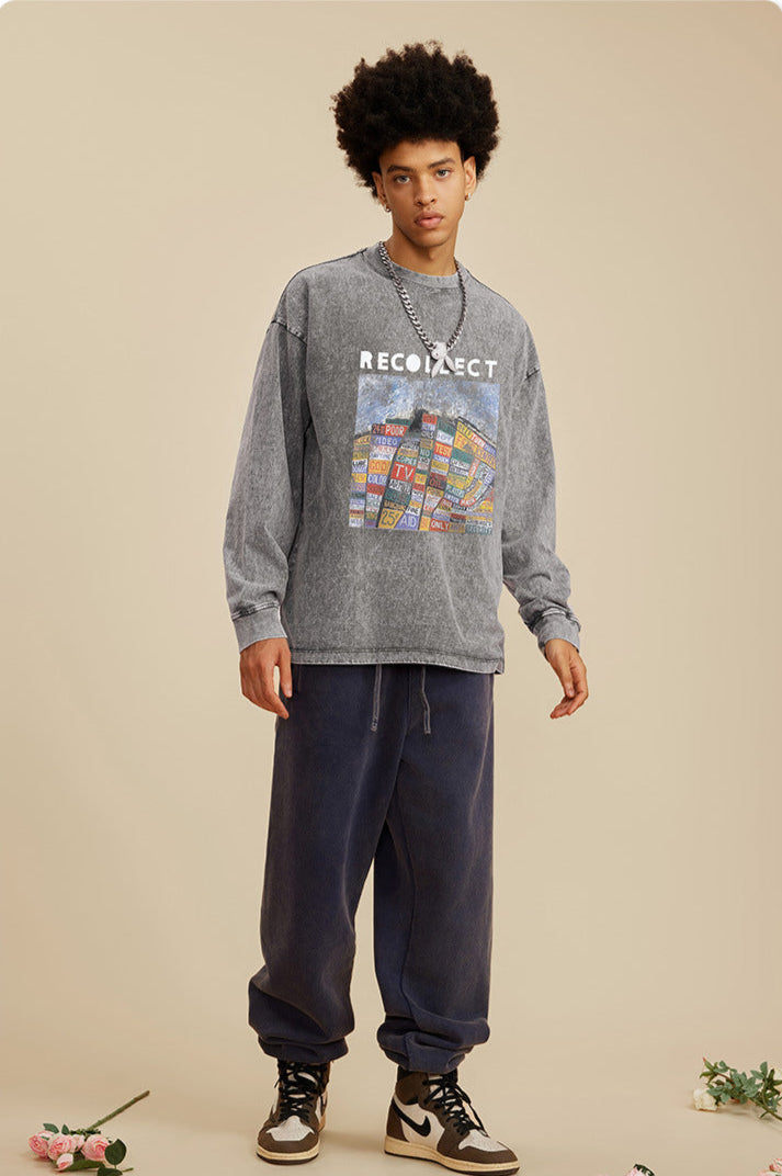 A male model wears a gray oversized "RECOLLECT" sweatshirt with a colorful print, navy sweatpants, and sneakers, posing neutrally