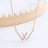 Rose gold W initial necklace with cubic zirconia detail against white background with pearl decor element