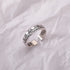 Sterling silver adjustable ring featuring Roman numerals and weekday engravings displayed on white textured fabric