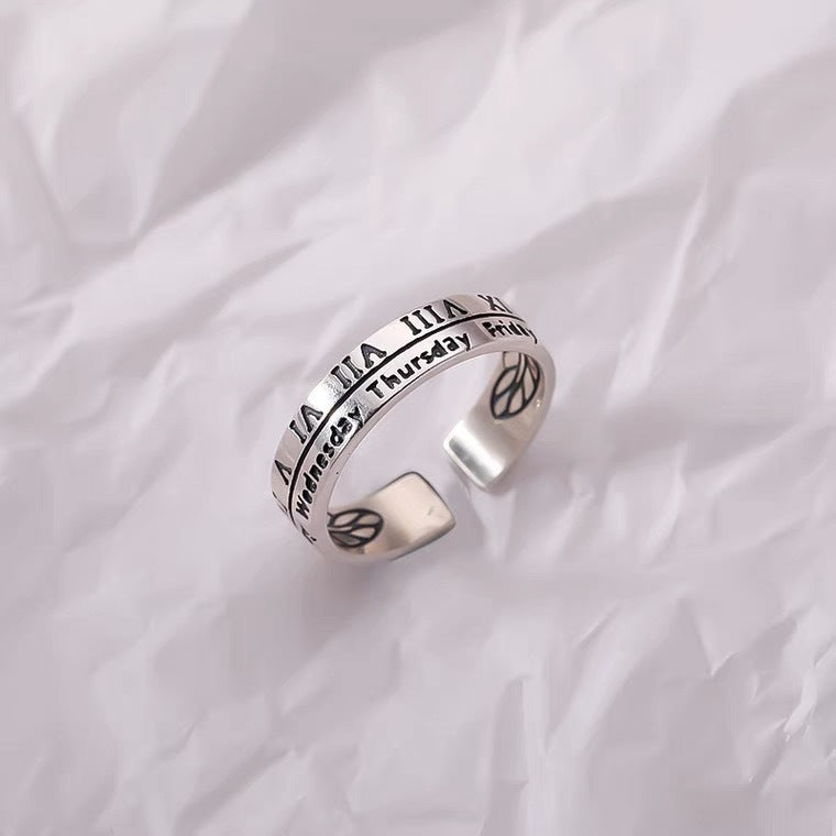 Sterling silver adjustable ring featuring Roman numerals and weekday engravings displayed on white textured fabric