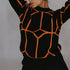 A model is posing with arms raised wearing a black knit sweater with orange geometric lines against gray background