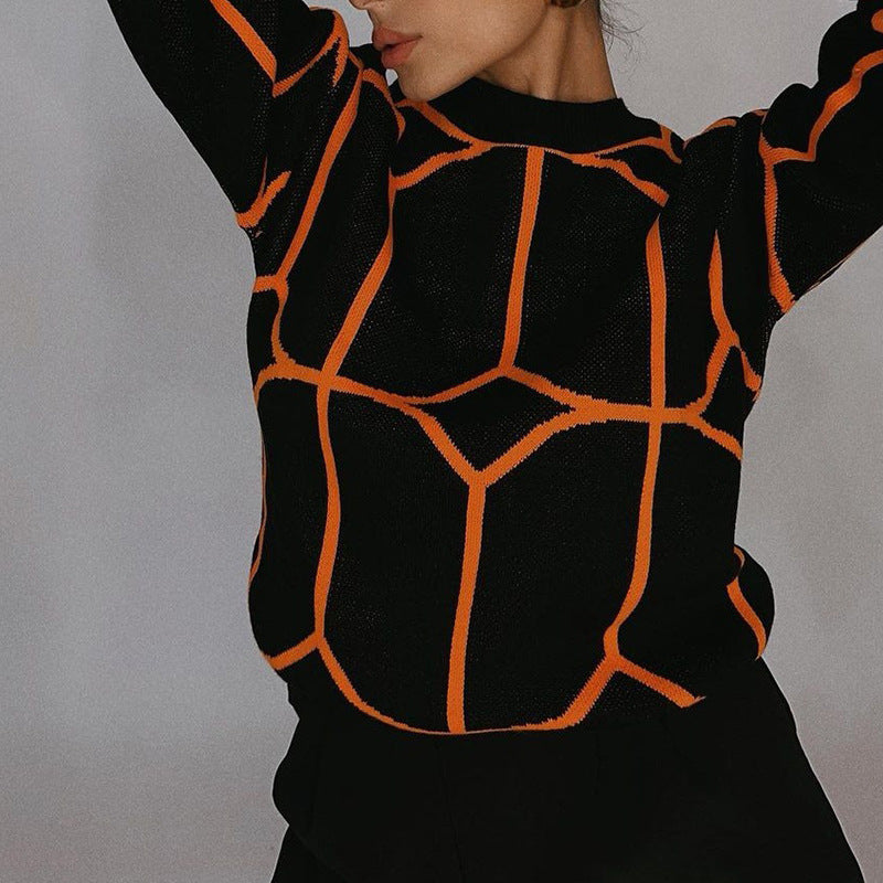 A model is posing with arms raised wearing a black knit sweater with orange geometric lines against gray background