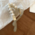 A gray acrylic hair claw clip featuring a heart-shaped loop lined with pearls, accented with a gold charm.