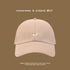 Beige baseball cap with small corgi embroidery shown against brown background