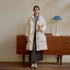 White down duffle coat styled with gray sweater dress and vintage sneakers against wooden dresser