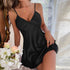 Woman in a black satin slip dress with a V-neck and flared hem, sitting near flowers