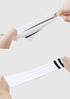 A close-up of hands stretching a white athletic crew sock with two black stripes, demonstrating its elasticity and soft fabric