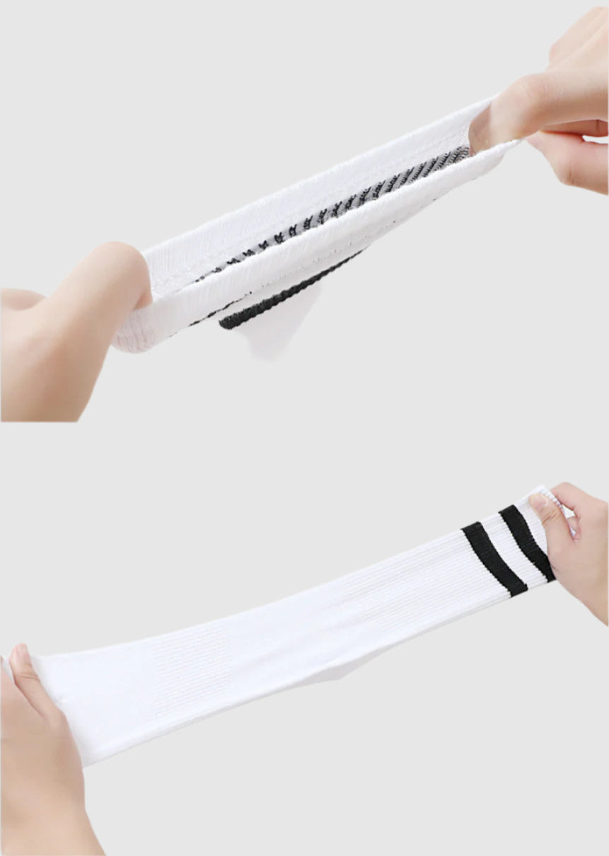 A close-up of hands stretching a white athletic crew sock with two black stripes, demonstrating its elasticity and soft fabric
