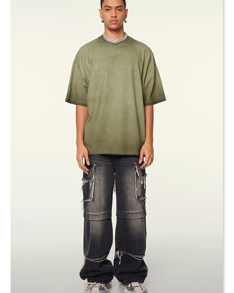Model with braided hair wearing olive green oversized t-shirt with slight wash effect, silver chain necklace, distressed cargo jeans