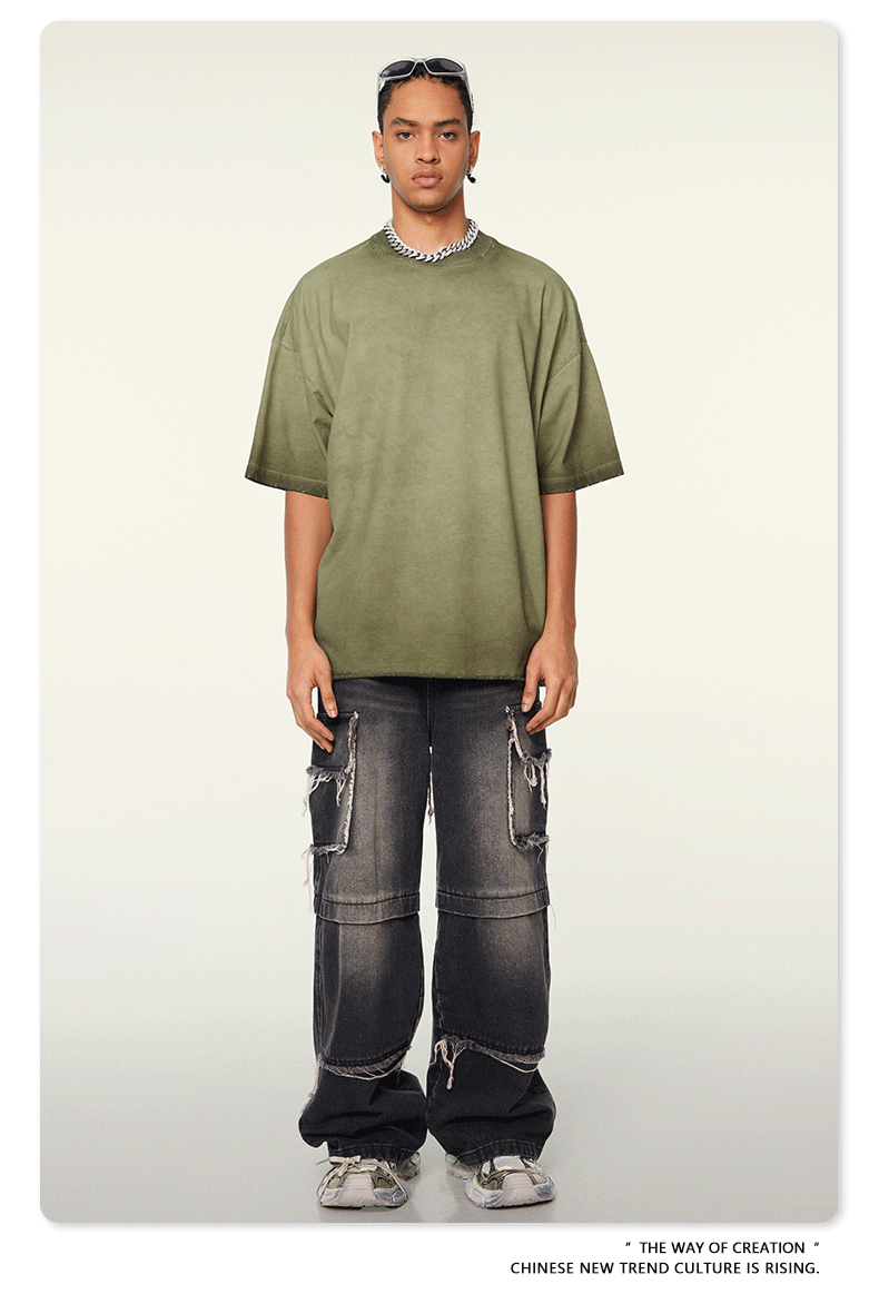 Model with braided hair wearing olive green oversized t-shirt with slight wash effect, silver chain necklace, distressed cargo jeans